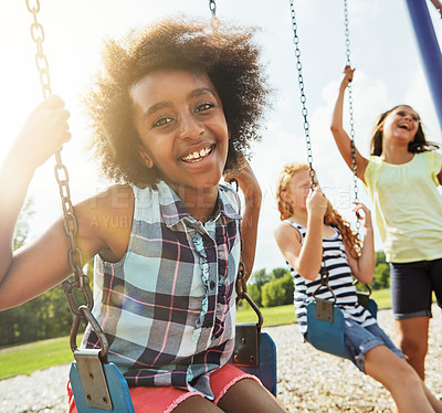 Buy stock photo Portrait of a young girl playing on a swing at the park with her friends