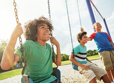 Buy stock photo Cropped shot of young boys playing on the swings at the park