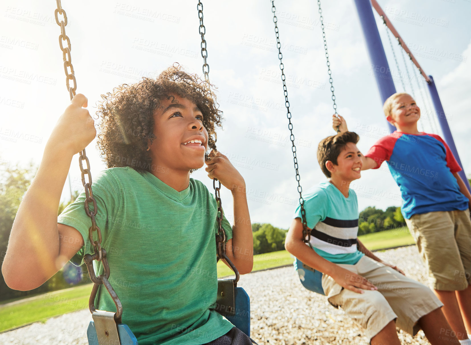 Buy stock photo Cropped shot of young boys playing on the swings at the park