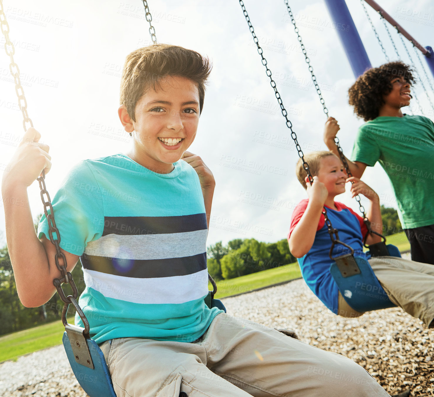 Buy stock photo Portrait of a young boy playing on a swing at the park with his friends