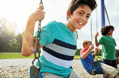 Buy stock photo Cropped shot of young boys playing on the swings at the park