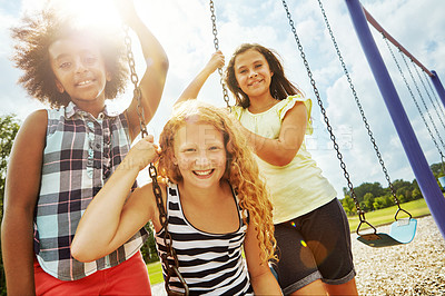 Buy stock photo Portrait of young girls playing on the swings at the park