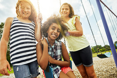 Buy stock photo Portrait of young girls playing on the swings at the park