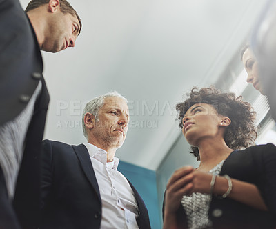 Buy stock photo Low angle shot of a group of businesspeople having a discussion in an office