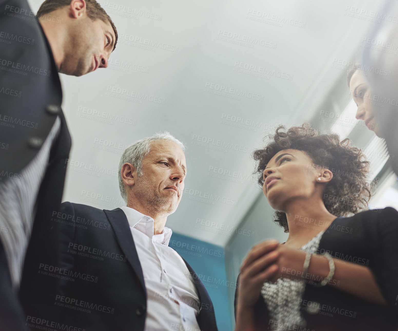 Buy stock photo Low angle shot of a group of businesspeople having a discussion in an office