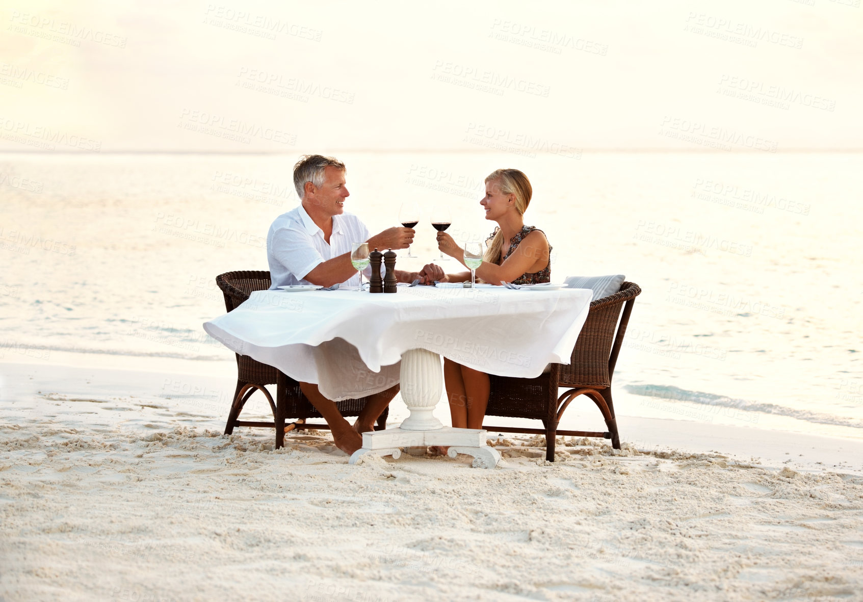 Buy stock photo Shot of a mature couple enjoying a romantic dinner on the beach