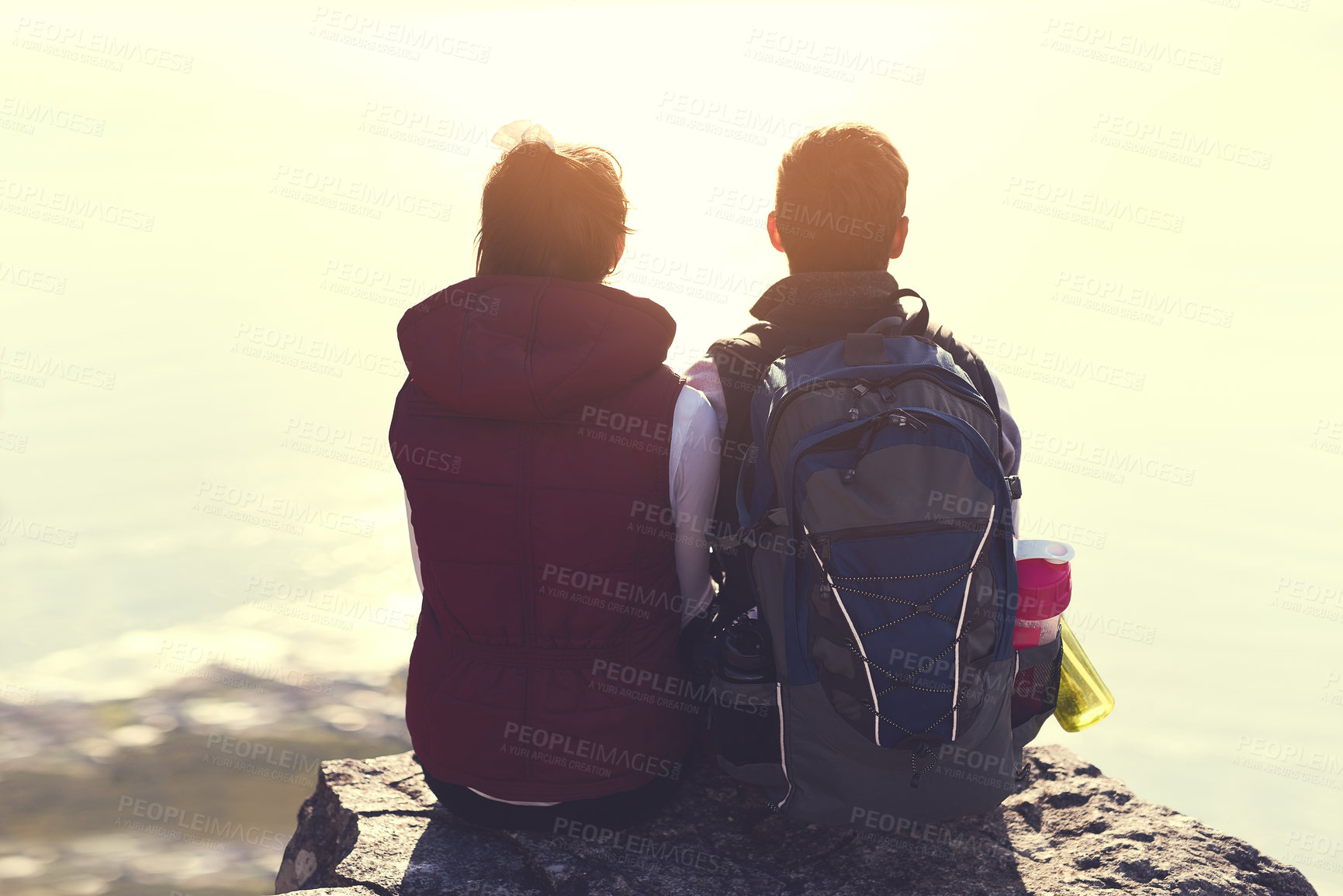 Buy stock photo Rearview shot of a young couple admiring the view from the top of a mountain