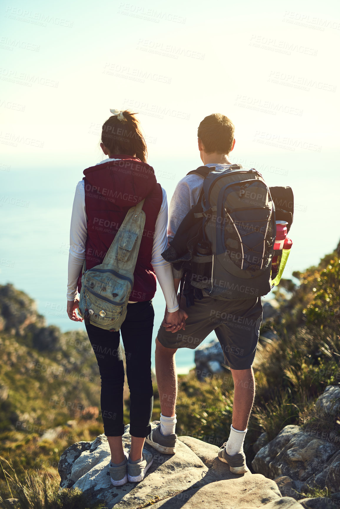 Buy stock photo Rearview shot of a young couple admiring the view from the top of a mountain