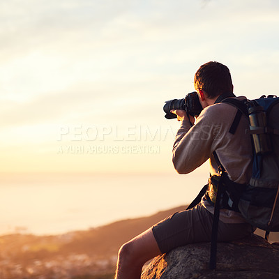 Buy stock photo Shot of a young photographer taking a picture from the top of a mountain
