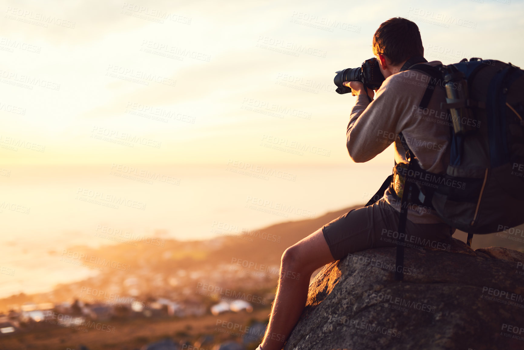 Buy stock photo Shot of a young photographer taking a picture from the top of a mountain