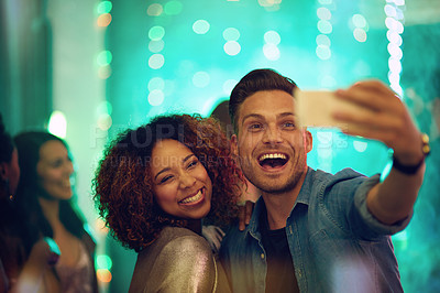 Buy stock photo Shot of a young couple taking a selfie in a nightclub