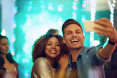 Buy stock photo Shot of a young couple taking a selfie in a nightclub