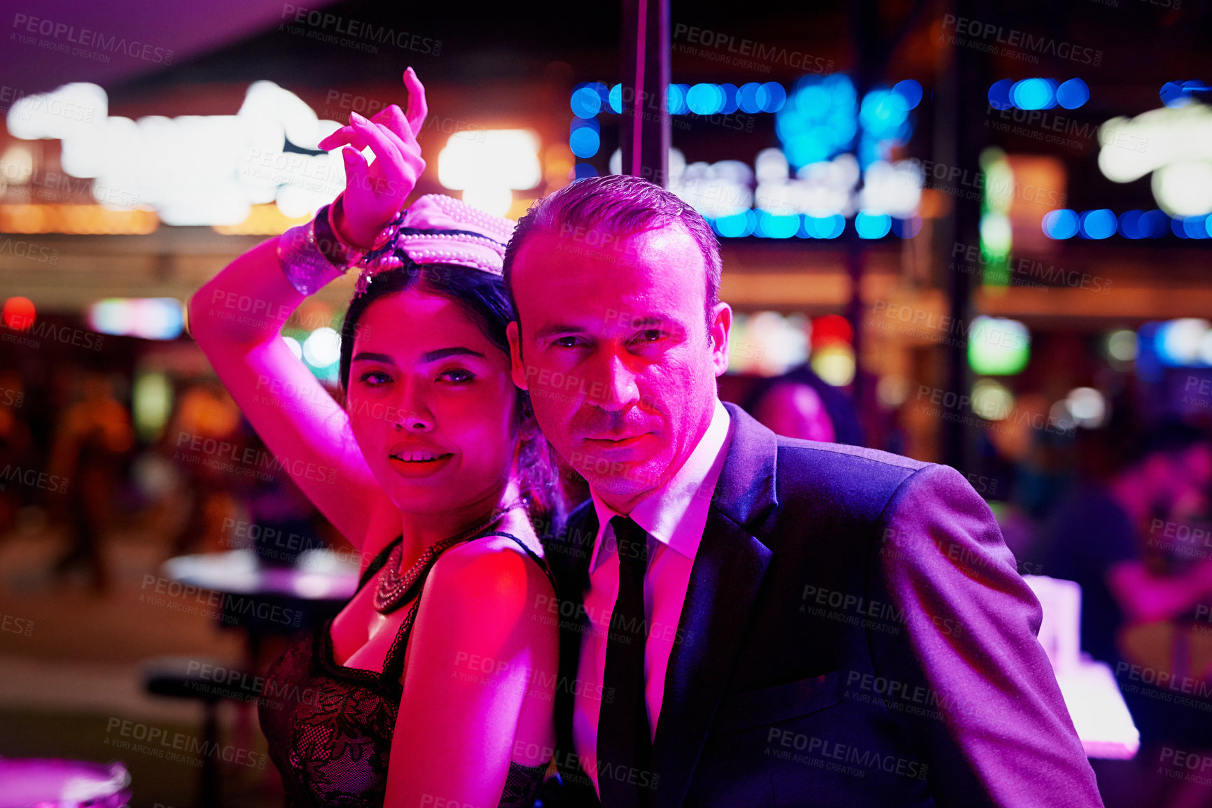 Buy stock photo Portrait of a seedy businessman standing with a bar girl in a go go bar in Thailand