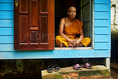 Buy stock photo Portrait of a buddhist monk sitting in the doorway of his home