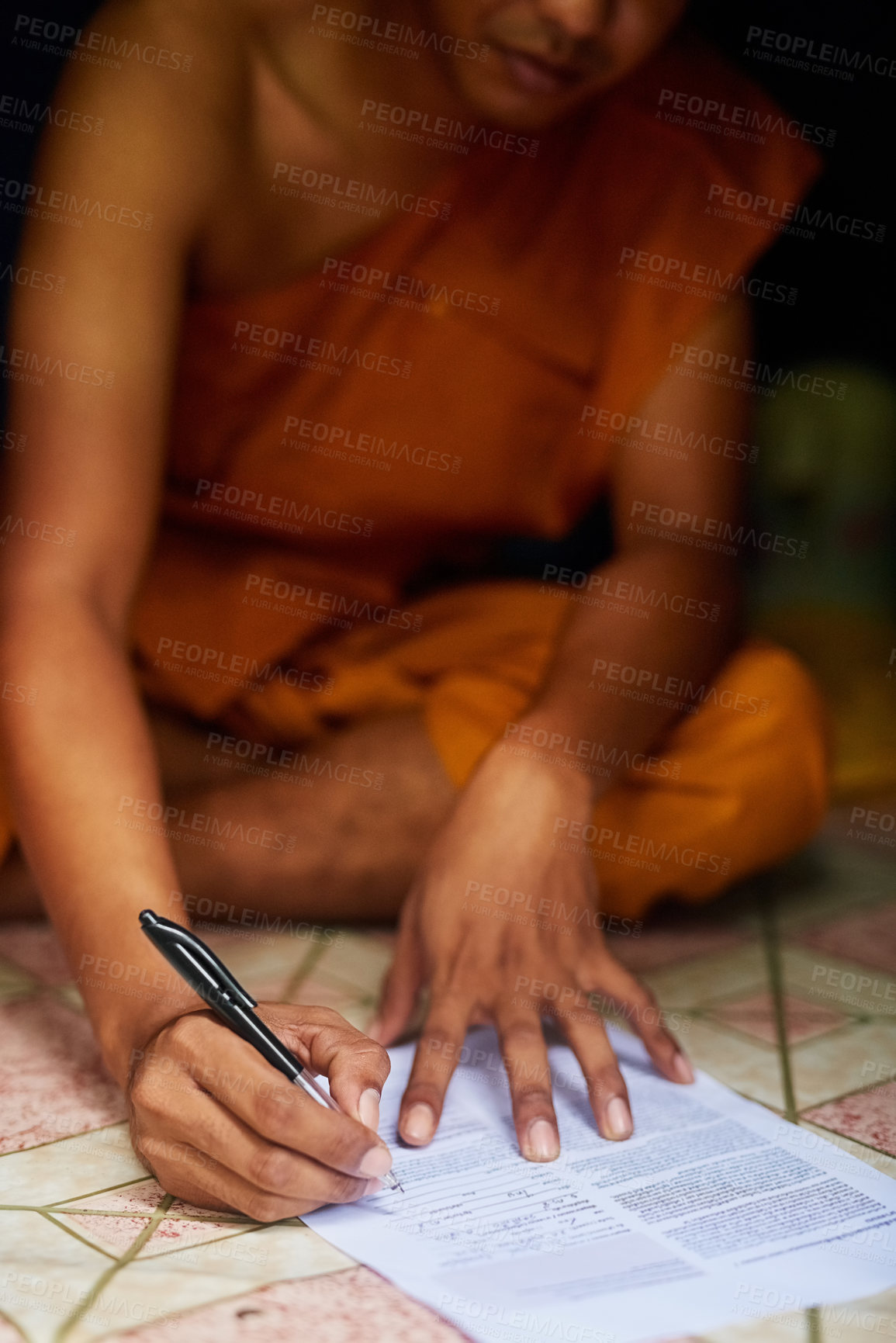 Buy stock photo Shot of an unidentifiable buddhist monk filling in a form while sitting in the doorway of his home
