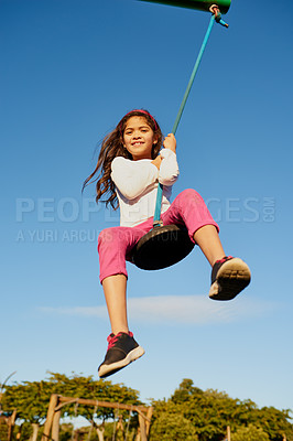Buy stock photo Portrait of a happy young girl playing on a swing at the park