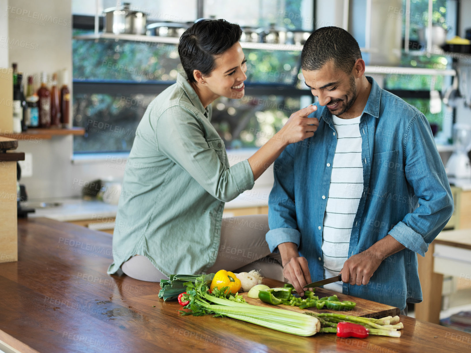 Buy stock photo Shot of a smiling young couple preparing a meal together in their kitchen