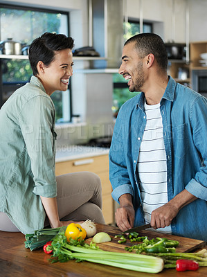 Buy stock photo Shot of a smiling young couple preparing a meal together in their kitchen