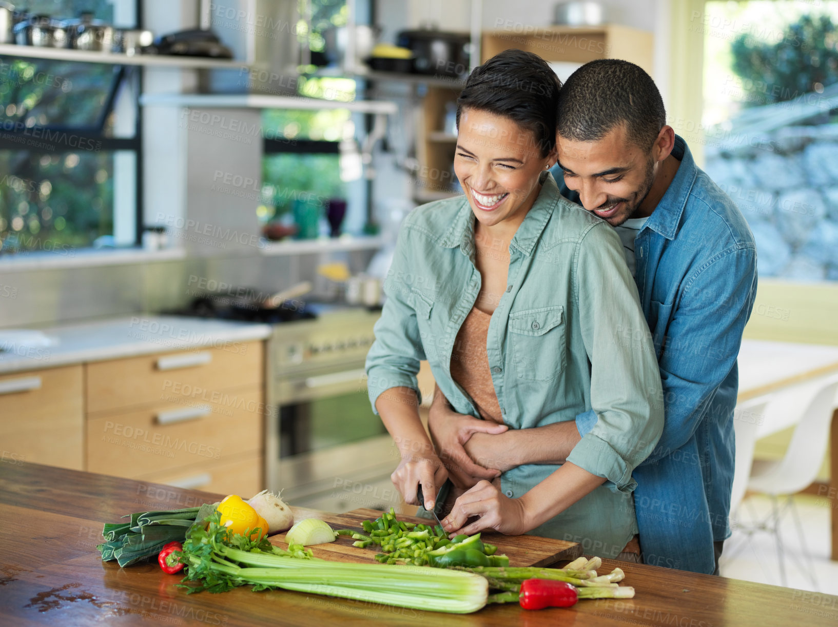 Buy stock photo Cooking, vegetables and couple embrace in kitchen for love, healthy food and bonding together with date. Smile, happy man and woman with knife for cutting, nutrition meal or preparation in home