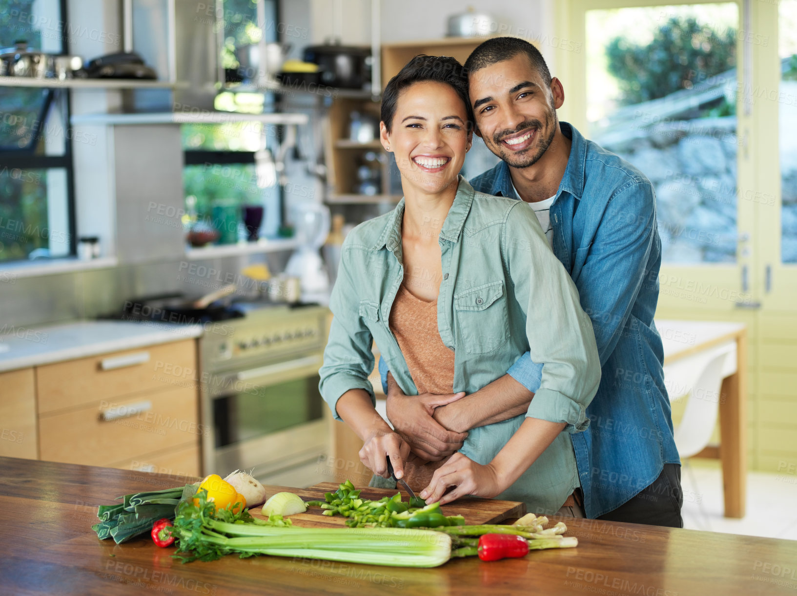 Buy stock photo Portrait, cooking and couple hug in kitchen for love, healthy food and bonding together with date. Vegetables, happy man and woman with knife for cutting, nutrition meal or preparation in home