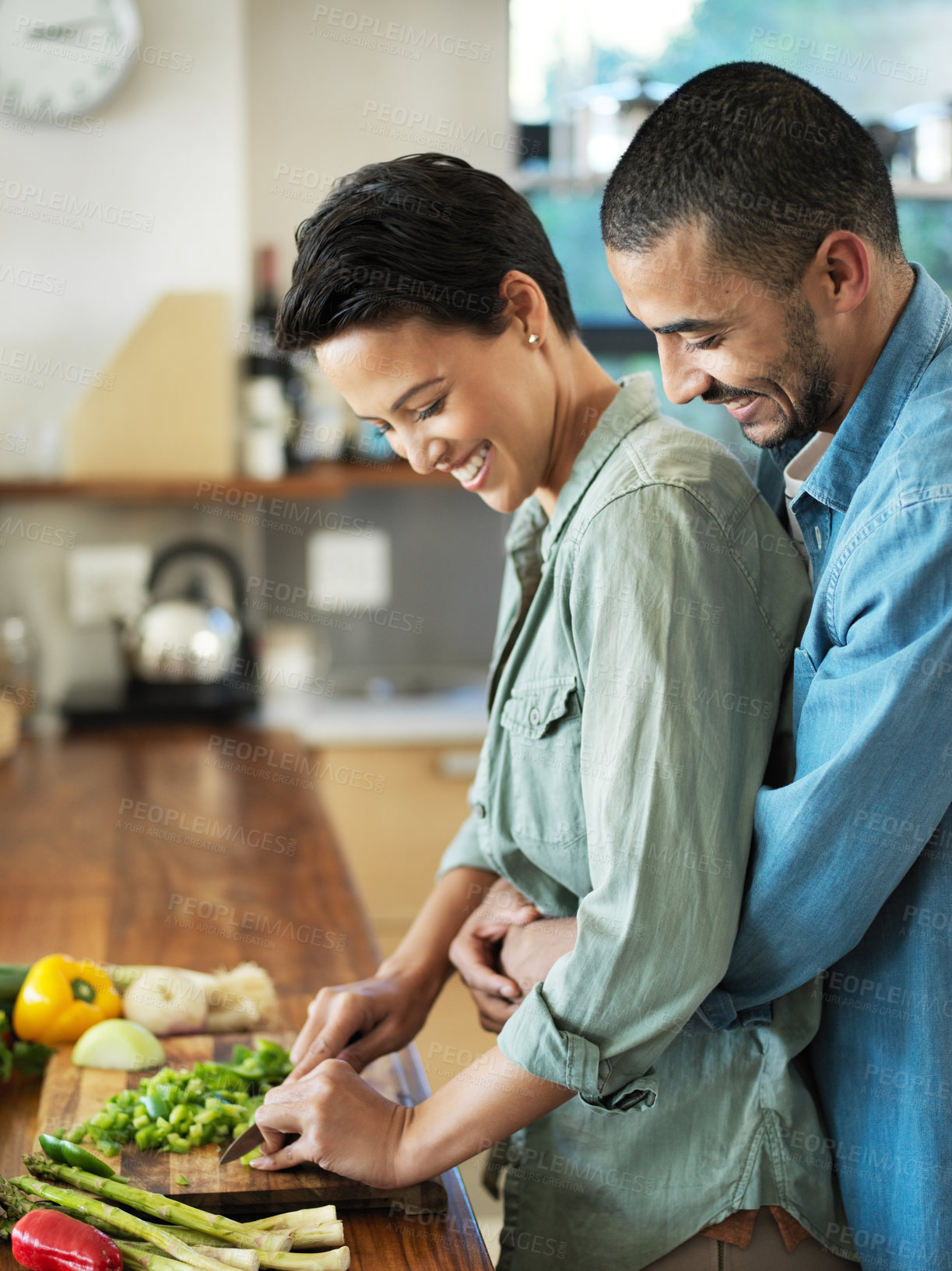 Buy stock photo Vegan cooking, hug and couple in kitchen with smile for love, healthy food and bonding together for date. Vegetables, happy man and woman with knife for cutting, nutrition meal or preparation in home
