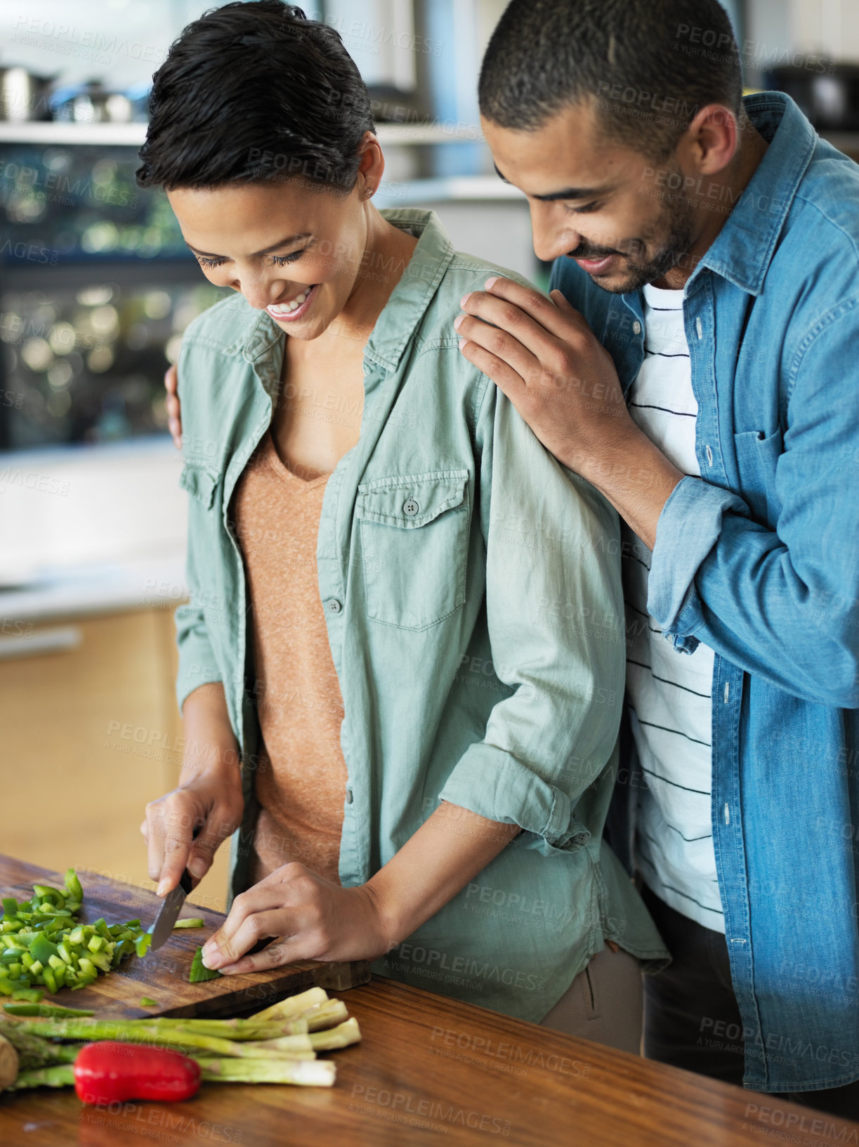 Buy stock photo Shot of an affectionate young couple preparing a meal together in their kitchen