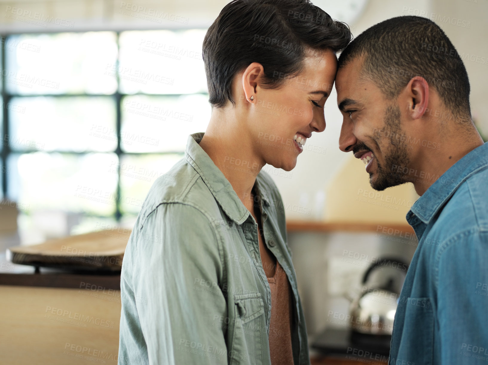 Buy stock photo Shot of an affectionate young couple standing playfully face to face in their kitchen