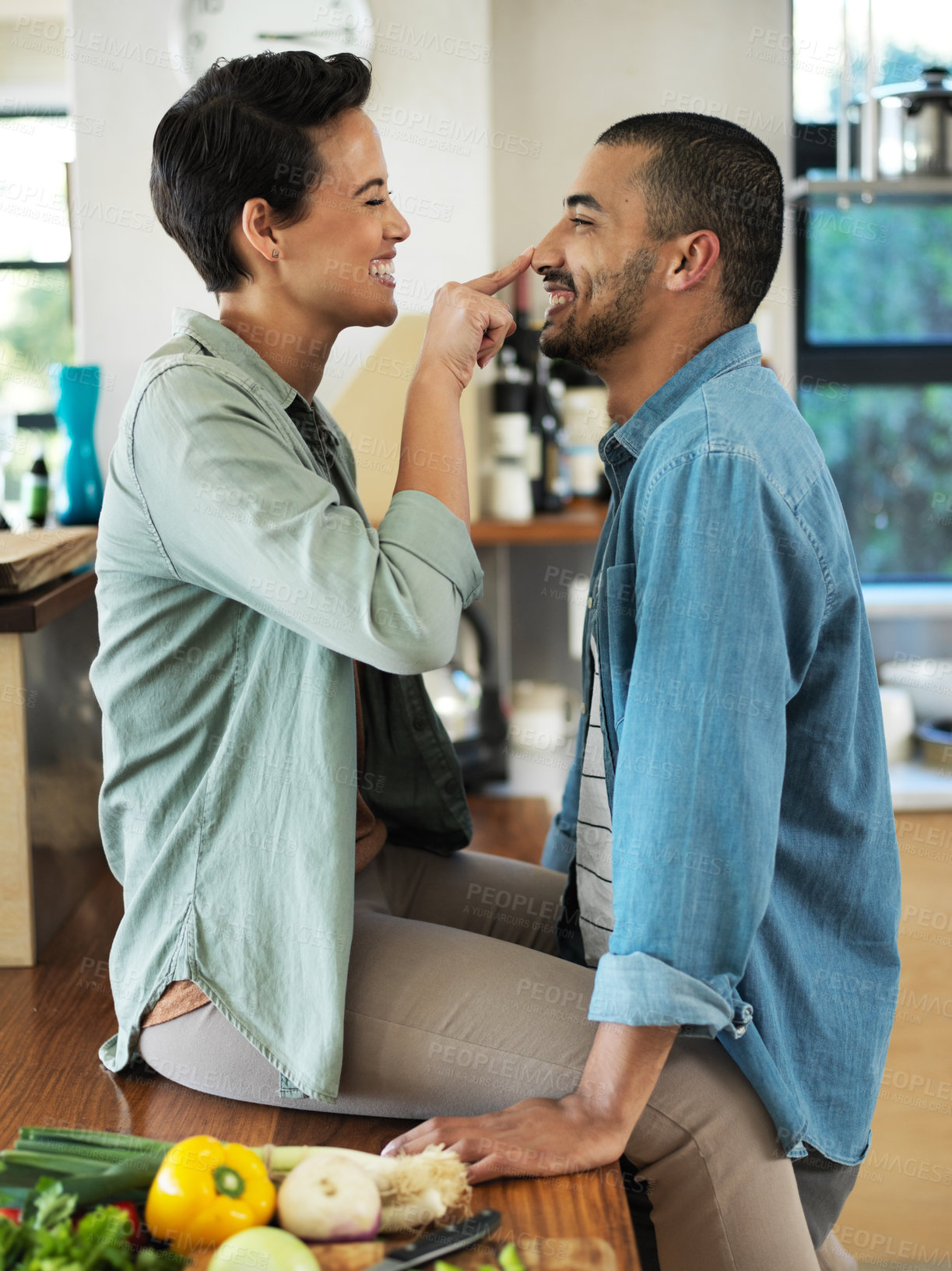 Buy stock photo Shot of an affectionate young couple preparing a meal together in their kitchen