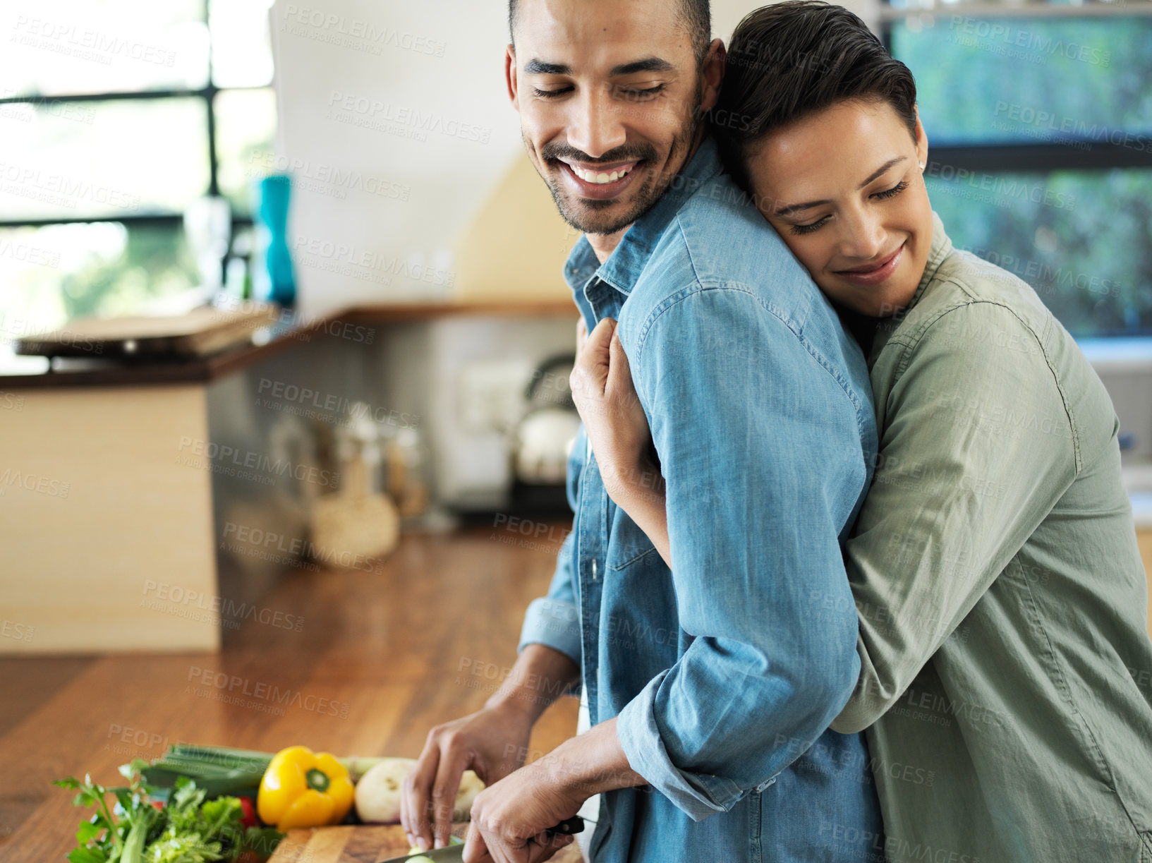 Buy stock photo Shot of an affectionate young couple preparing a meal together in their kitchen