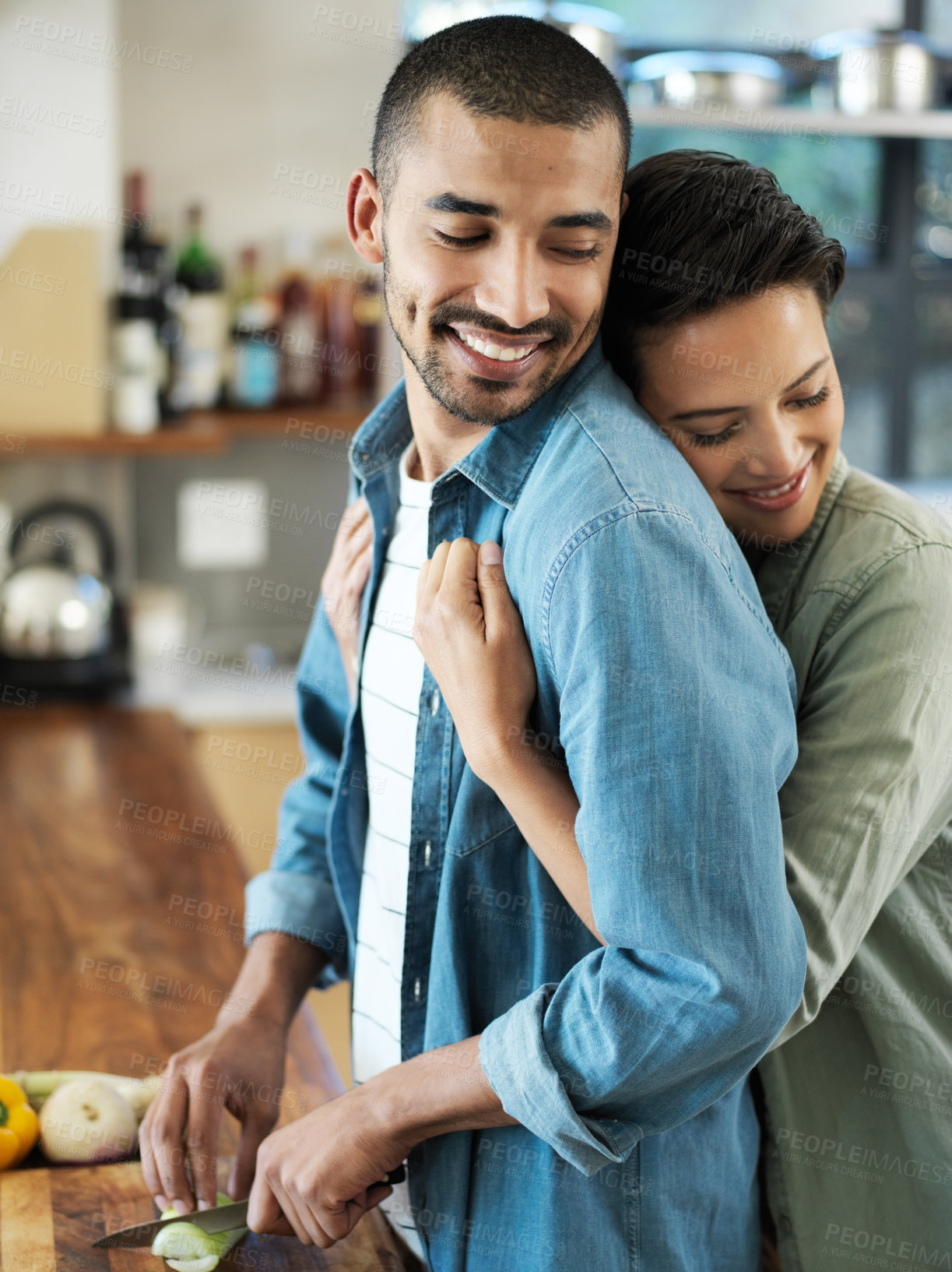 Buy stock photo Shot of an affectionate young couple preparing a meal together in their kitchen