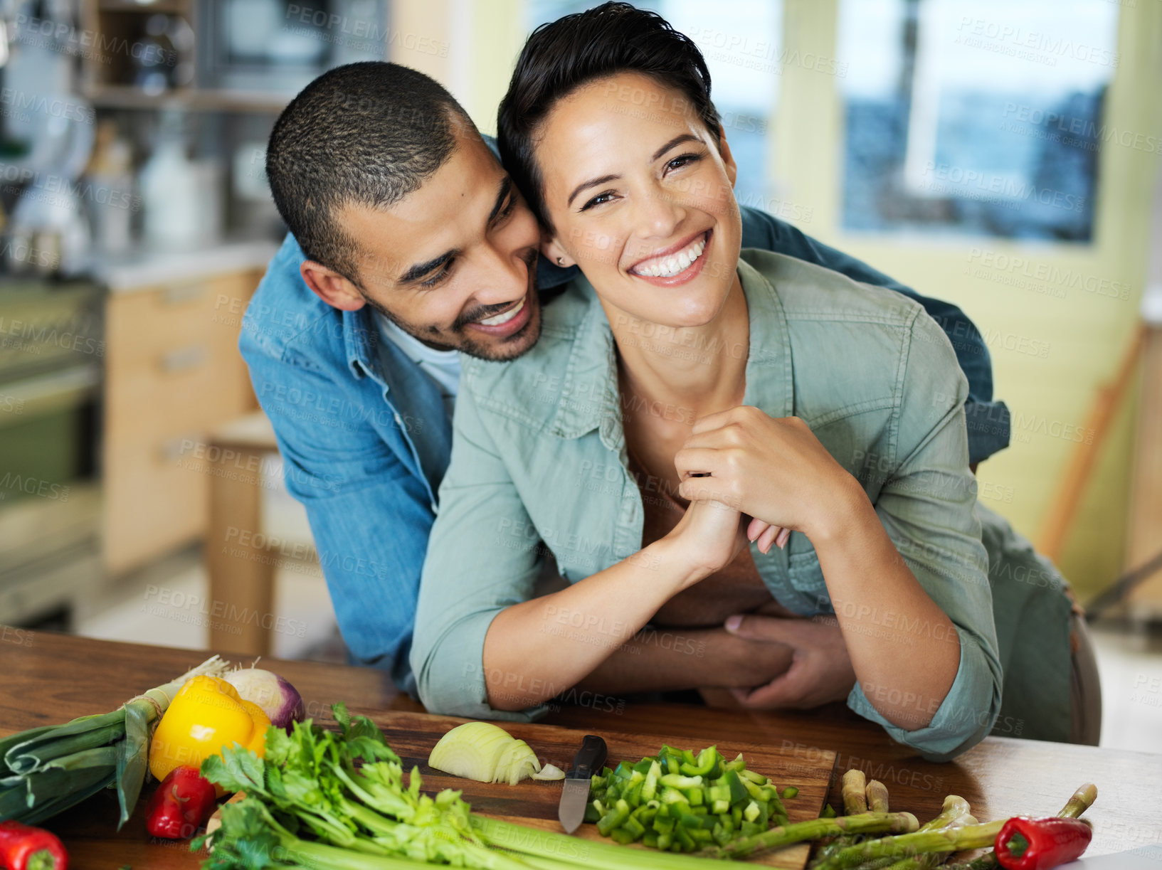 Buy stock photo Cooking, vegan and couple hug at kitchen counter for love, healthy food and bonding together on date. Vegetables, happy man and woman with smile for cutting, nutrition meal or preparation in home