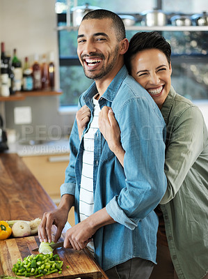 Buy stock photo Portrait of an affectionate young couple preparing a meal together in their kitchen