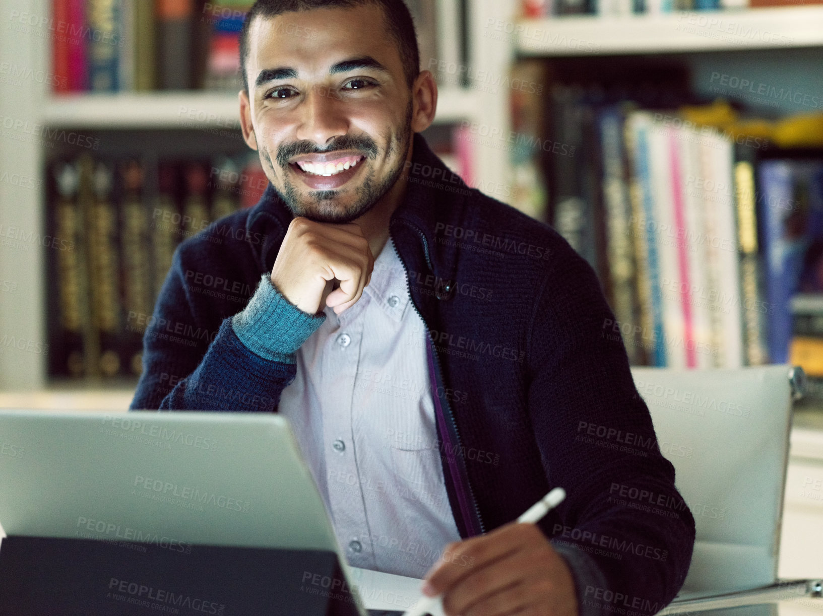 Buy stock photo Portrait of a smiling young man working on a digital tablet in his home office in the early evening