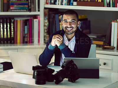 Buy stock photo Portrait of a smiling young photographer working on a digital tablet and laptop in his home office in the early evening