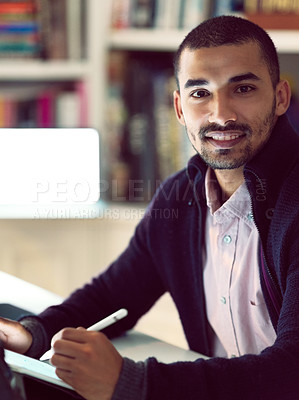 Buy stock photo Shot of a focused young man working on a digital tablet in his home office in the early evening