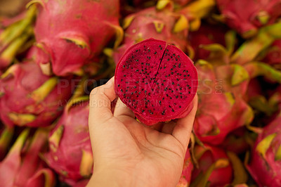 Buy stock photo Shot of an unidentifiable woman holding a halved dragon fruit at a fruit market