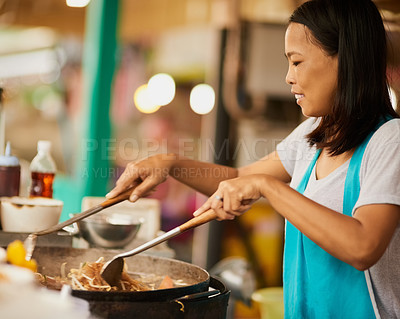 Buy stock photo Shot of a happy food vendor preparing a Thai dish at a food market