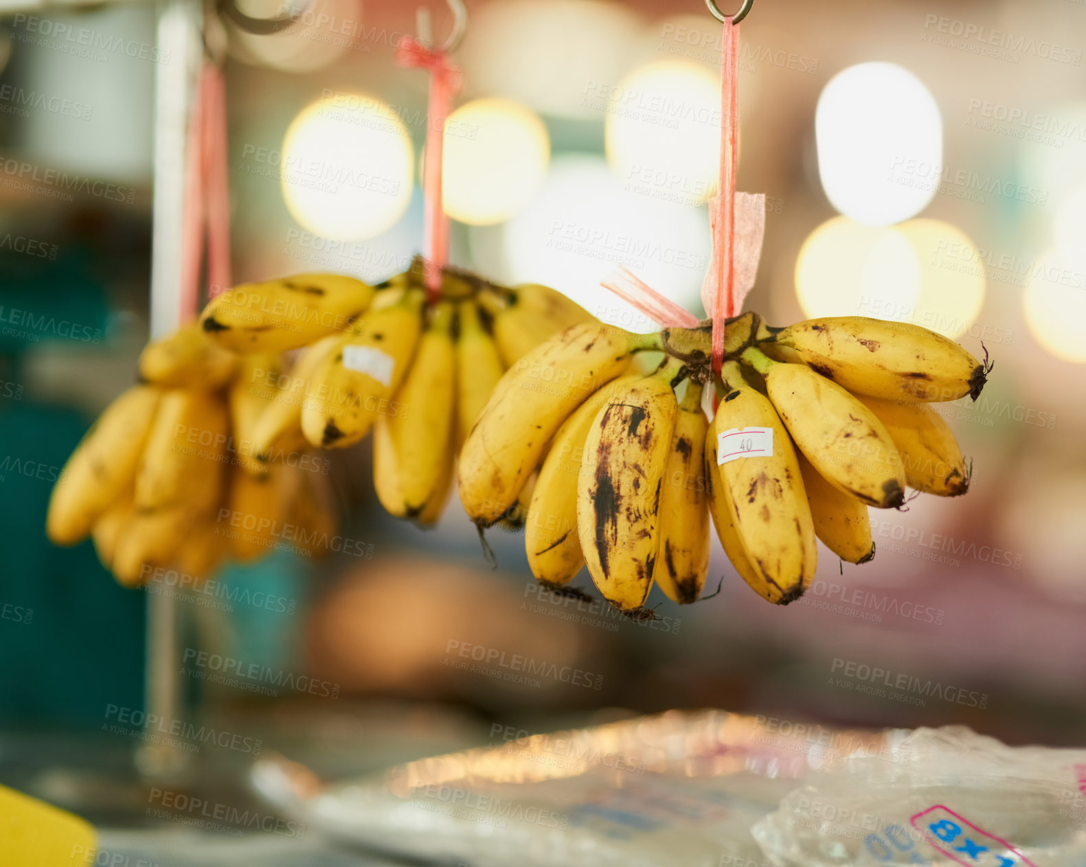 Buy stock photo Shot of bunches of bananas hanging from strings at a food market