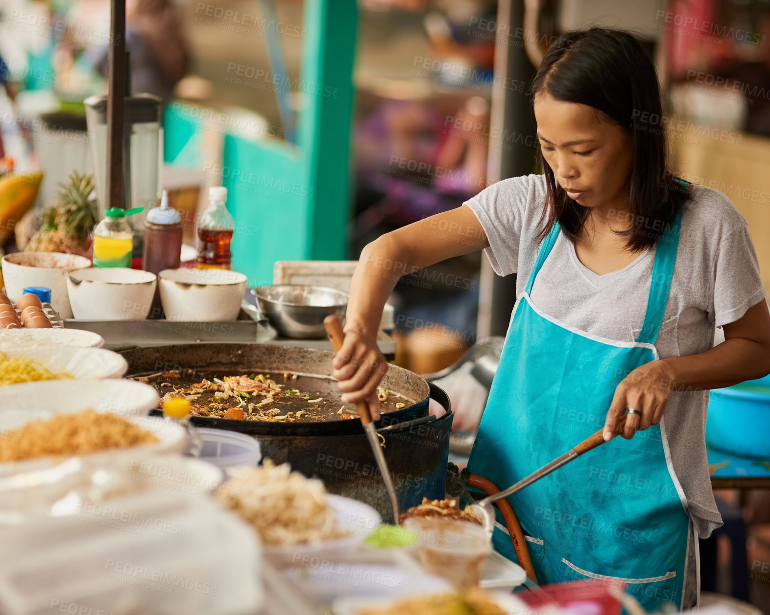 Buy stock photo Shot of a food vendor preparing a Thai dish at a food market