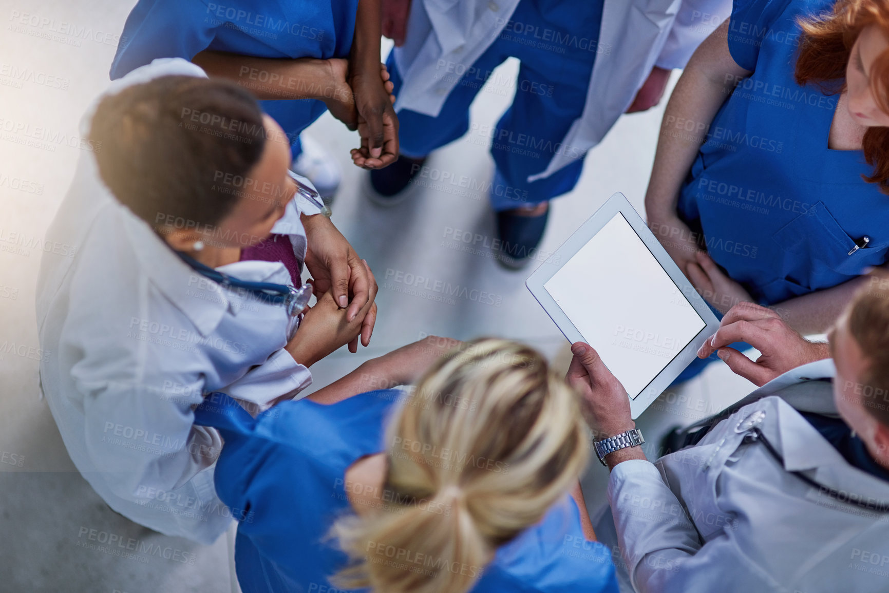 Buy stock photo High angle shot of a team of doctors using a digital tablet together