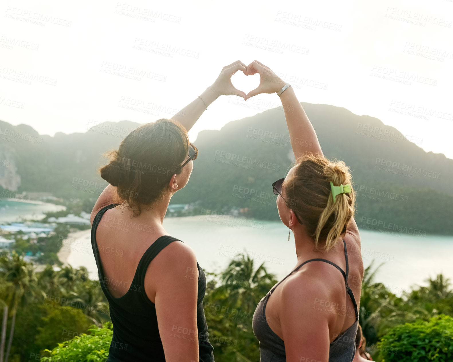 Buy stock photo Shot of two friends making a heart shape with their hands while on holiday in Thailand