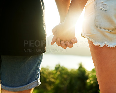 Buy stock photo Rearview shot of an unrecognizable young couple standing hand in hand outside