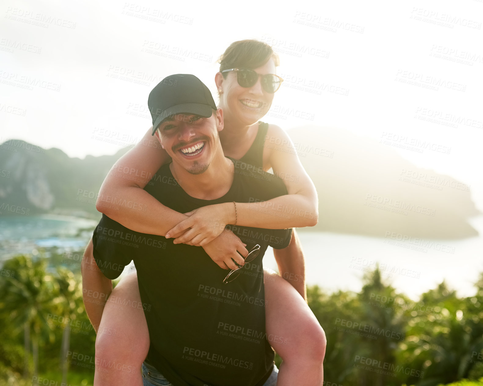 Buy stock photo Shot of a young man carrying his girlfriend on his back while holidaying together in Thailand