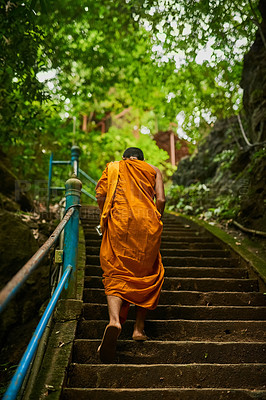 Buy stock photo Rearview shot of a buddhist monk climbing a flight of stone steps