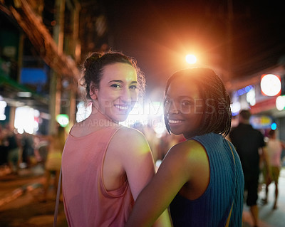 Buy stock photo Portrait of two happy young friends exploring a foreign city at night