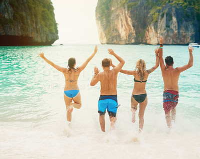 Buy stock photo Rearview shot of a group of friends running into the ocean together