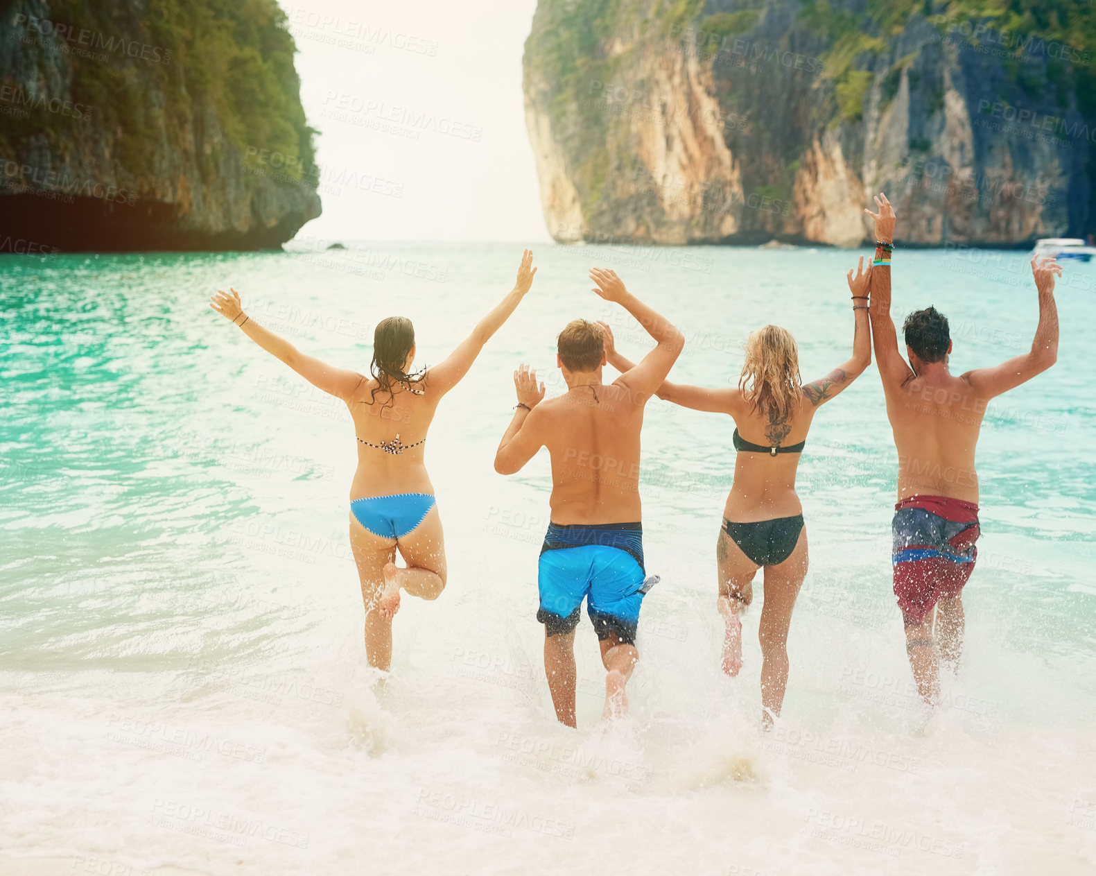 Buy stock photo Rearview shot of a group of friends running into the ocean together