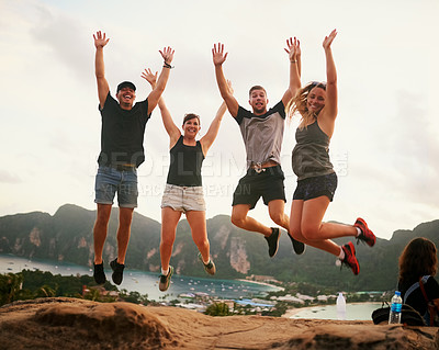 Buy stock photo Shot of a happy young couple jumping in front of an island landscape