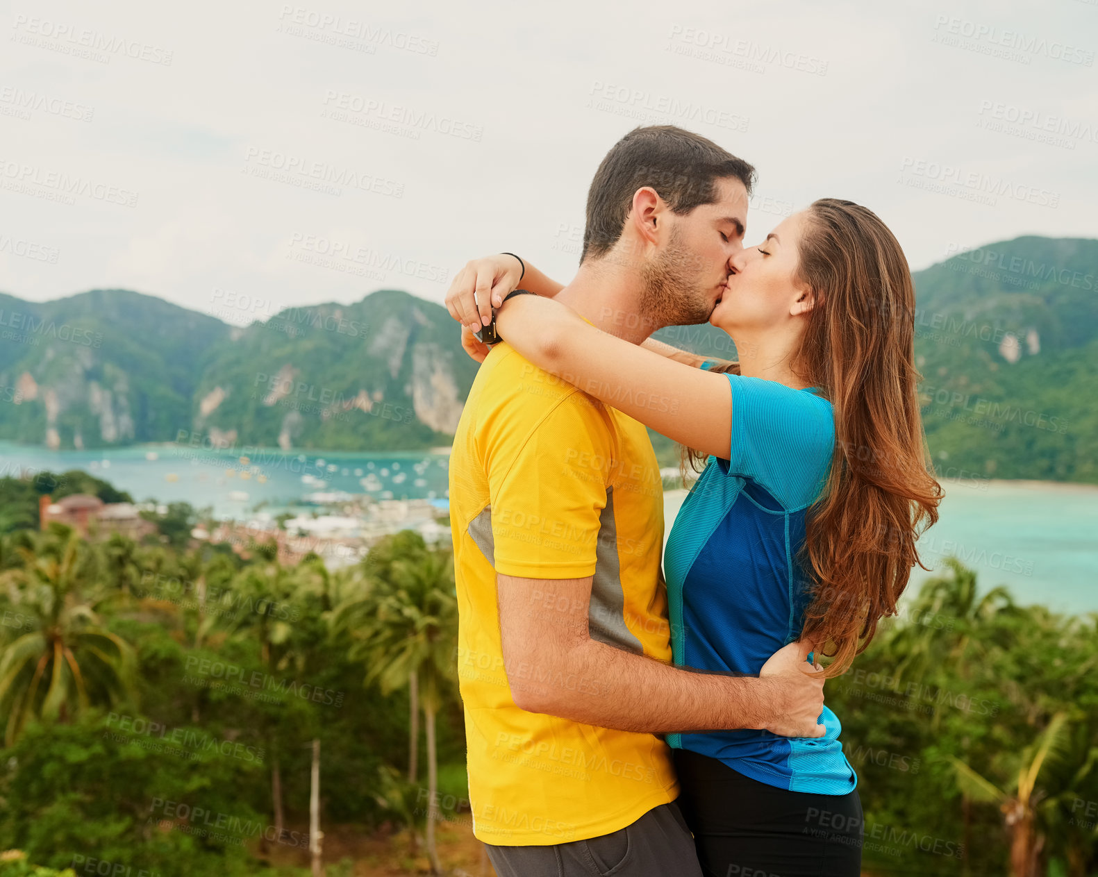 Buy stock photo Shot of a happy young couple kissing in front of an island landscape