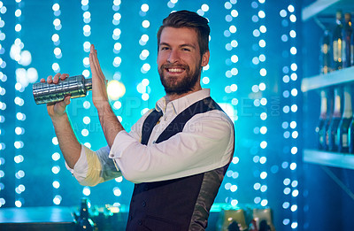 Buy stock photo Portrait of a handsome young bartender mixing drinks in a nightclub
